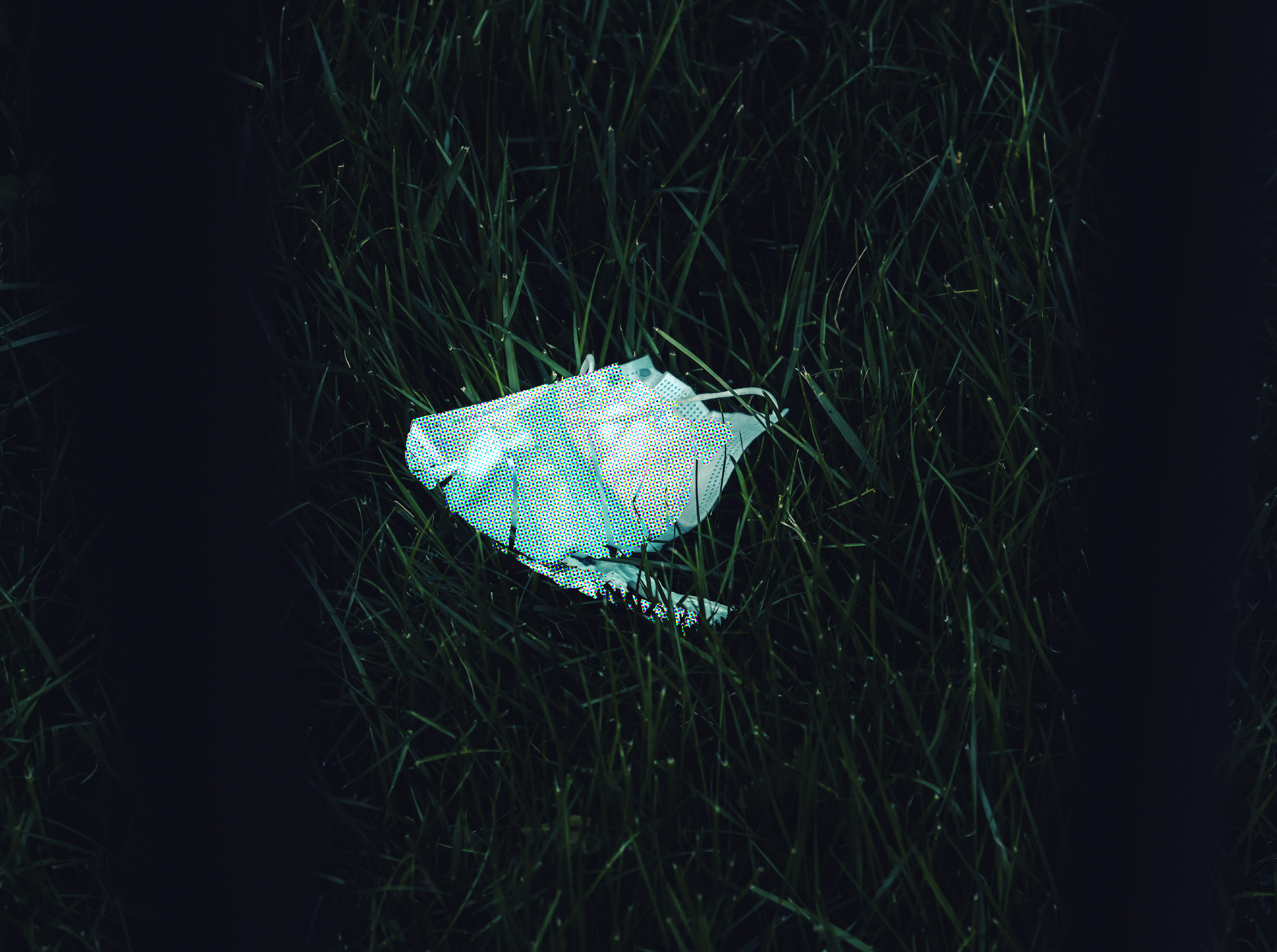 Edited picture of a discarded face mask on ground.
